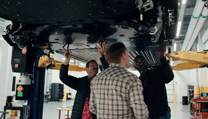Assoalho Novos Veículos Elétricos Homens conferindo o inferior de veículo