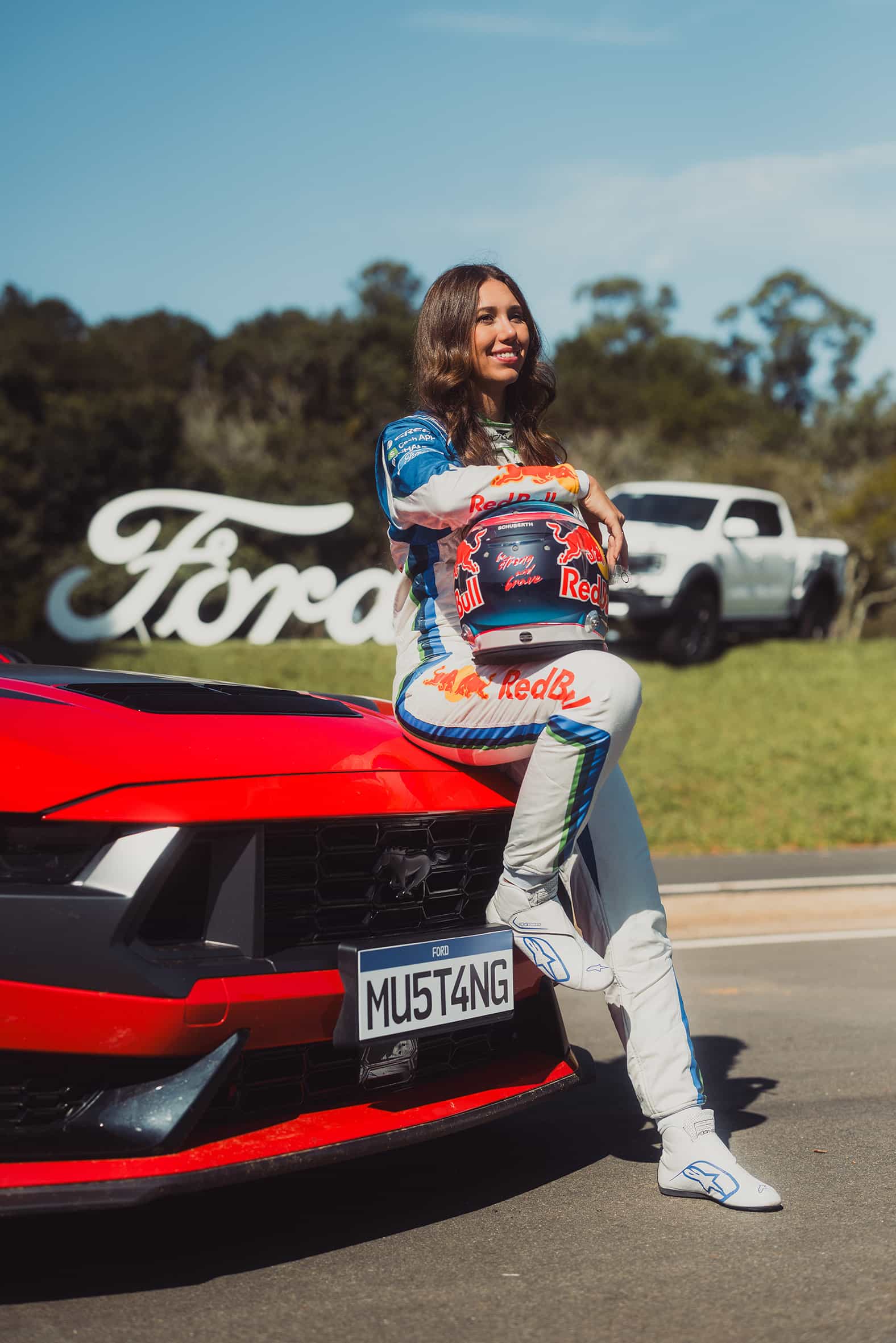 Rafaela Ferreira sentada no capô de um Mustang Dark Horse