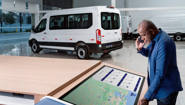 Homem Falando ao Celular e Consultando Mapa, Com Transit Minibus ao Fundo, representando Ford Pro Conectividade