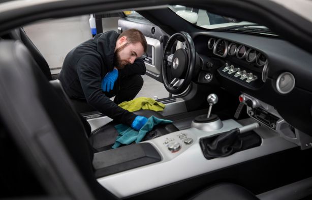 Homem limpando interior de carro esportivo.