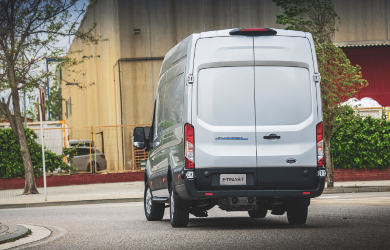 Visão traseira da Ford E-Transit Furgão Branca rodando na estrada