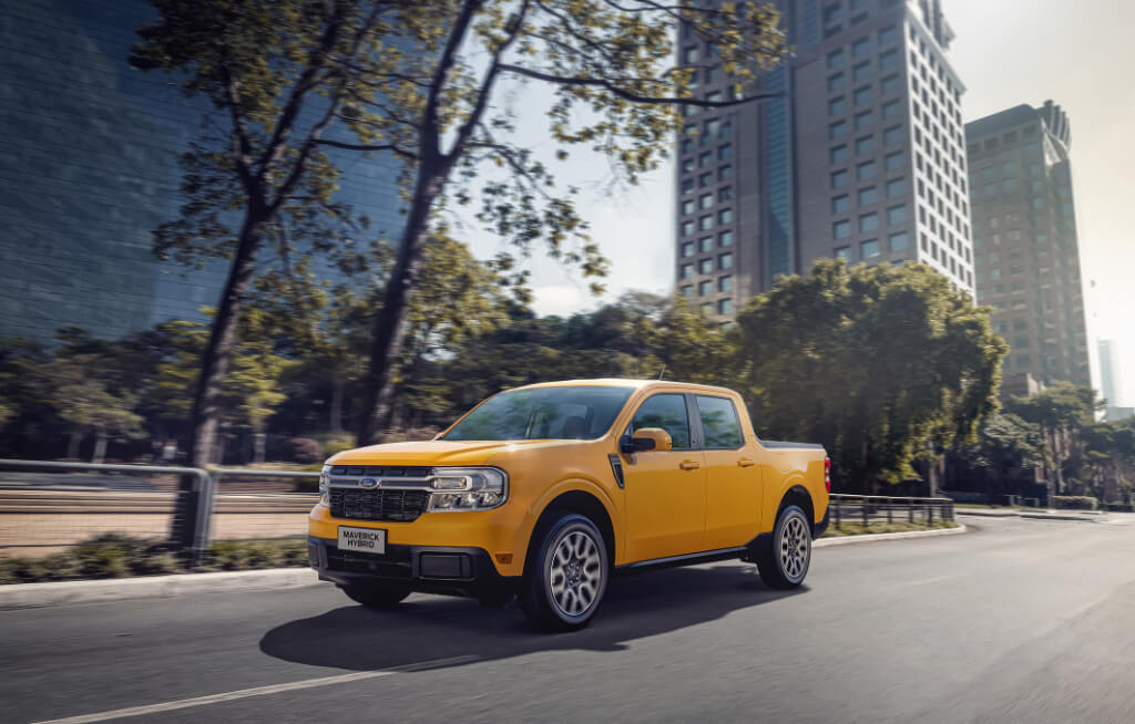 Ford Maverick Hybrid Laranja Rodando em Ambiente Urbano