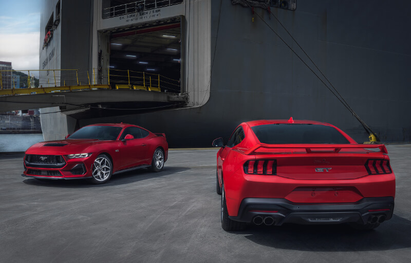 Visão traseira e frontal do novo Ford Mustang GT Performance Vermelho no porto com um navio ao fundo