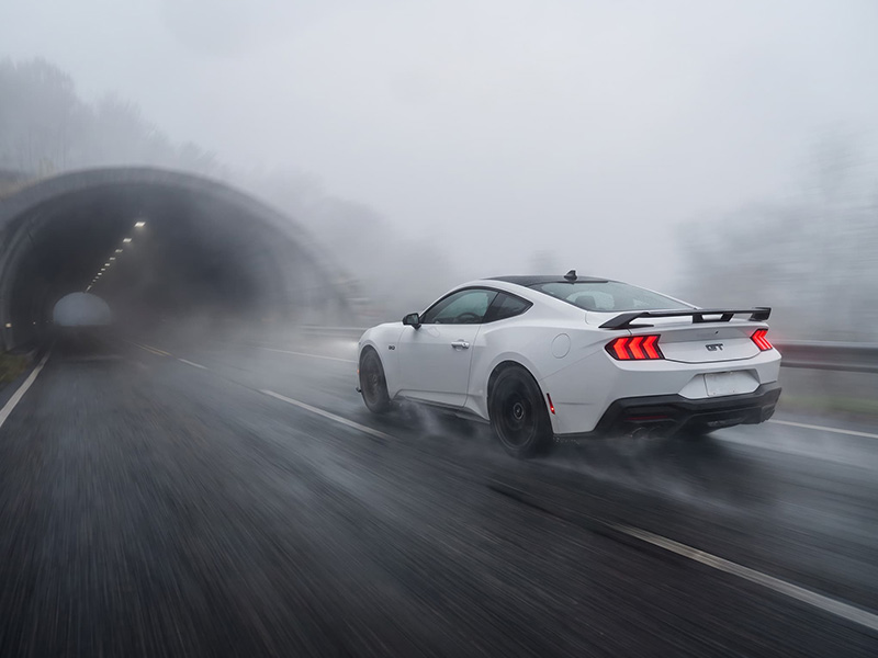 Mustang GT Performance 2026 branco no túnel Mustang GT Performance 2026 branco visto de trás em uma estrada com neblina