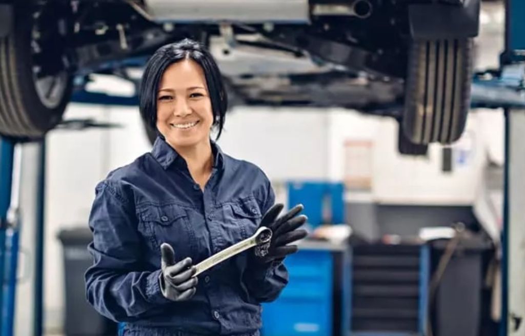 Mulher uniformizada sorrindo em uma oficina