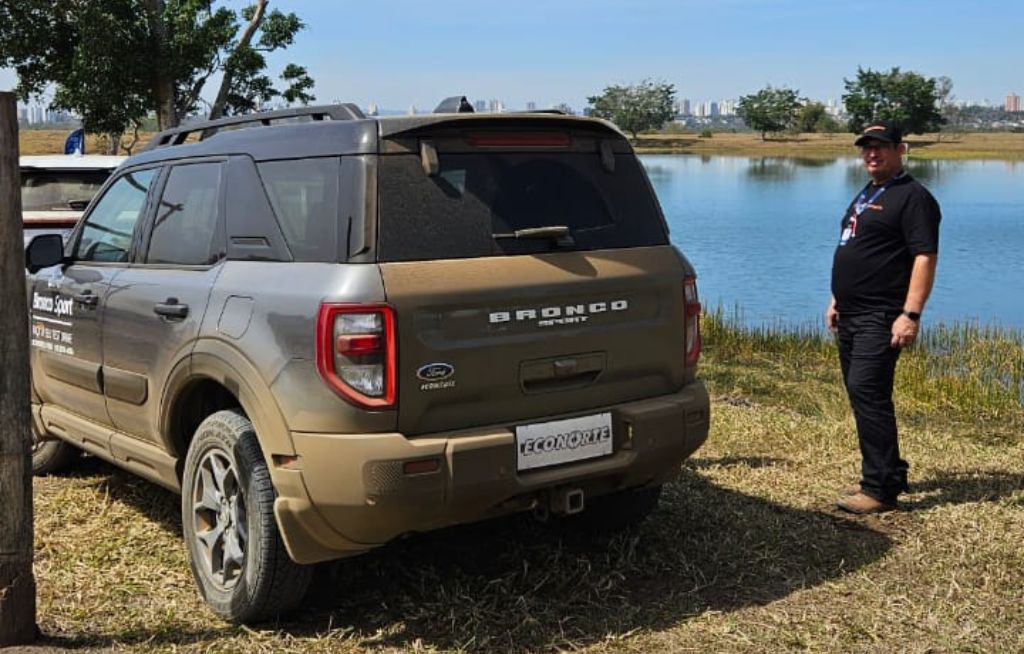 Ford Bronco estacionado próximo a um lago e um homem posando para foto