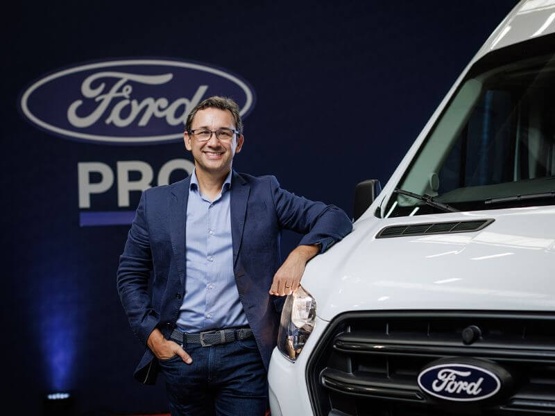 Hombre apoyado en un vehículo Ford con fondo de Ford Pro