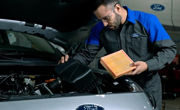 Trabajador de servicio revisando el motor de un vehículo Ford=