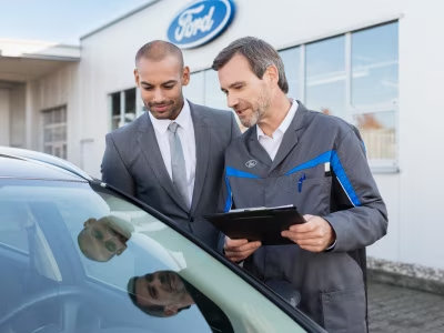 Cliente y trabajador de Ford revisando un automóvil