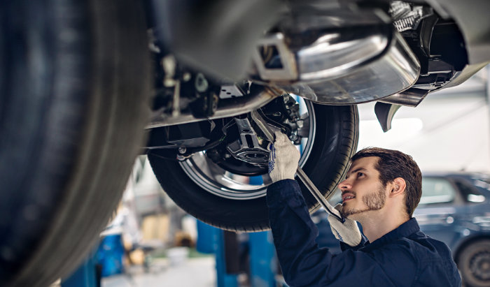 Hombre trabajando en el taller Ford arreglando con sus herramientas un carro
