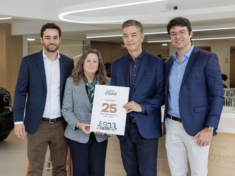 Grupo de executivos Ford segurando placa comemorativa de aniversário