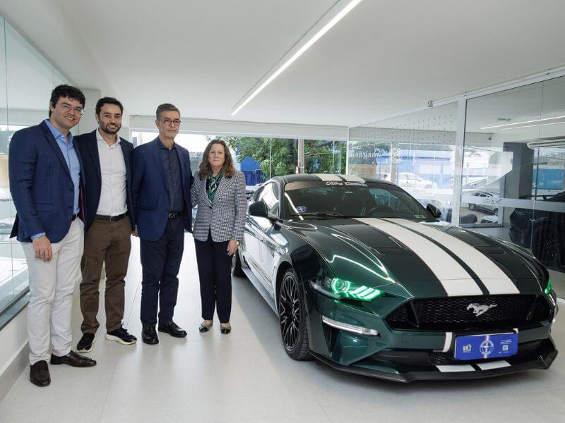 Grupo de executivos Ford segurando ao lado de um Mustang GT