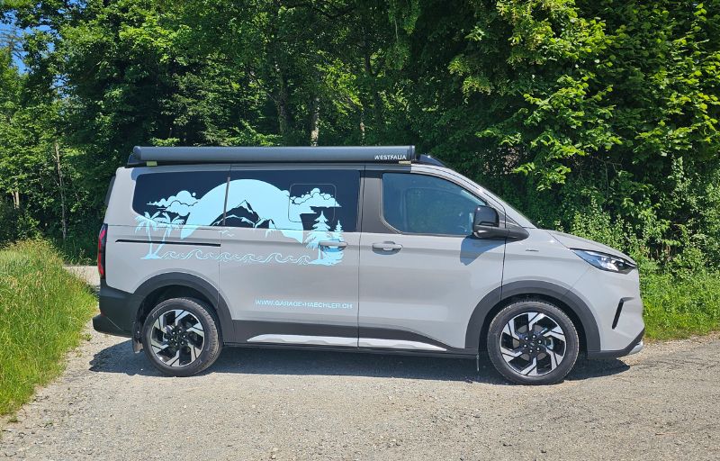Grauer Ford Nugget in Seitenansicht parkt auf Kieselsteinstrasse