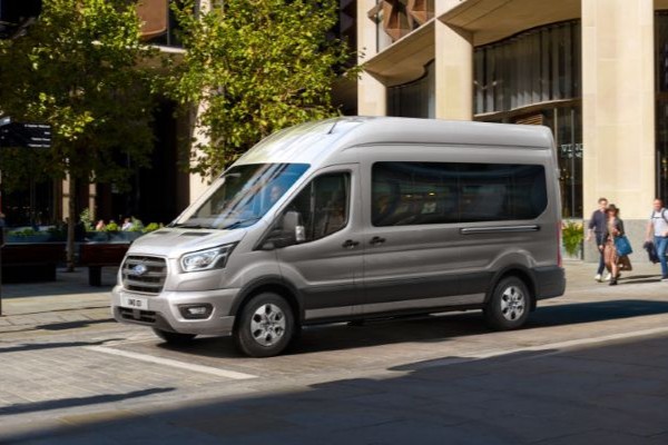 Transit Minibus steht an Ampel in Stadt und ist von Menschen umgeben