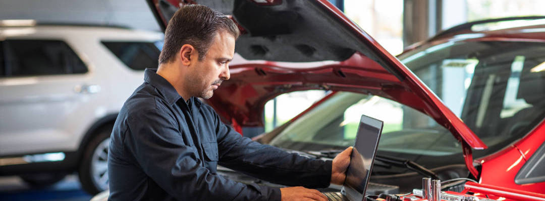 Mann in Werkstatt liest Daten auf einem Laptop