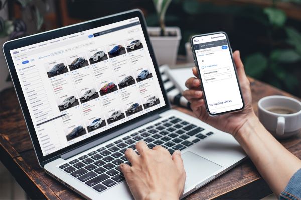 Autokauf online - Person am Laptop und Handy