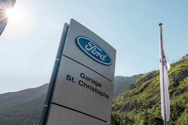 Ford-Logo auf Säule vor Garage vor sonnigem Himmel
