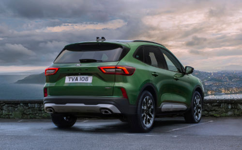 Ford Kuga parcheggiata vicino a un muro di pietra con vista sulla città