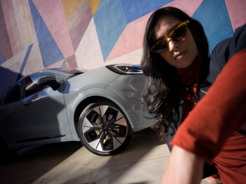 Donna alza il braccio davanti a Ford Puma su sfondo colorato