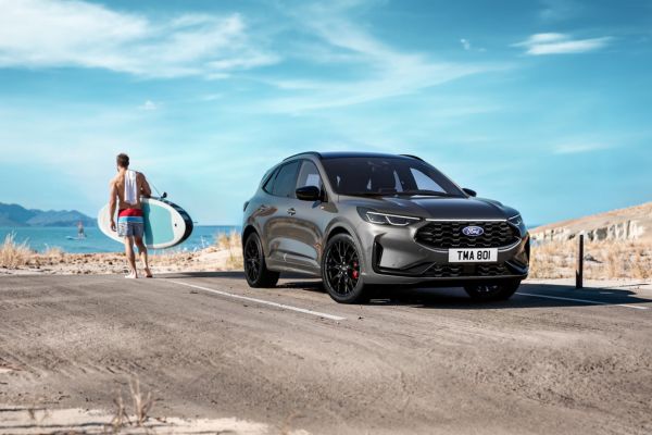 Surfer neben geparkten grauen Ford Kuga am Strand