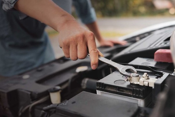 Initiativbewerbung Automechaniker hält Schraubenschlüssel in der Hand und repariert Motor eines Fahrzeugs