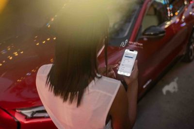 Frau hält Smartphone vor Fahrzeug