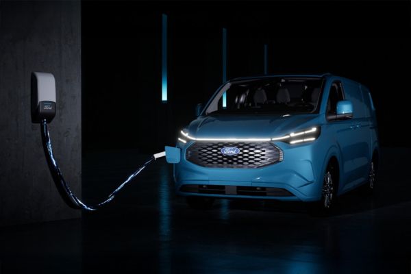 Une Ford E-Transit Custom bleue est en train de se recharger à une borne de recharge.