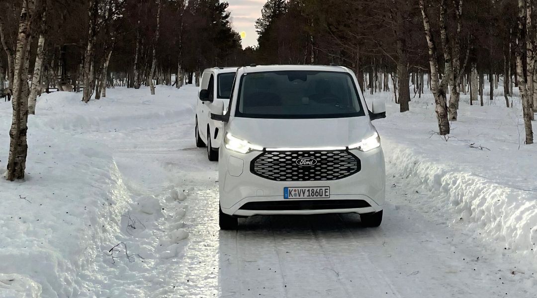 Weisser E-Transit Custom unterwegs auf schneebedeckter Strasse