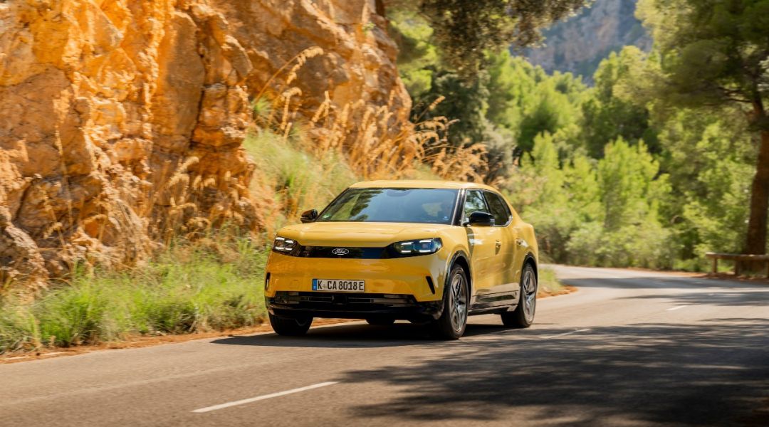 Gelber Ford Capri unterwegs auf Strasse mit karger Felswand im Hintergrund