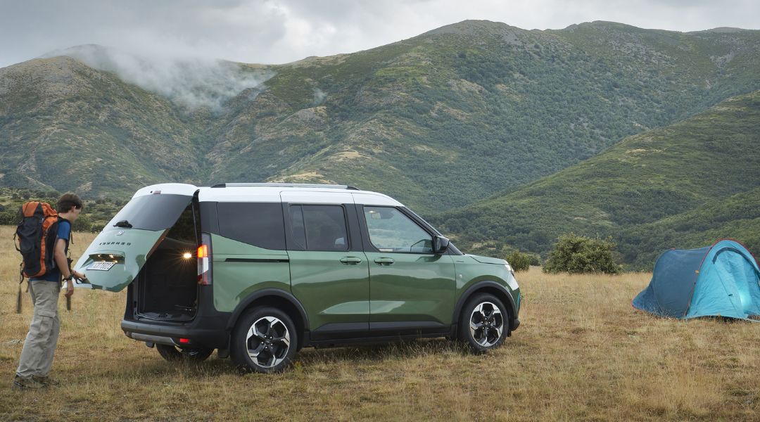 Ford E-Tourneo Ford E-Tourneo steht neben Campingzelt vor Gebirge