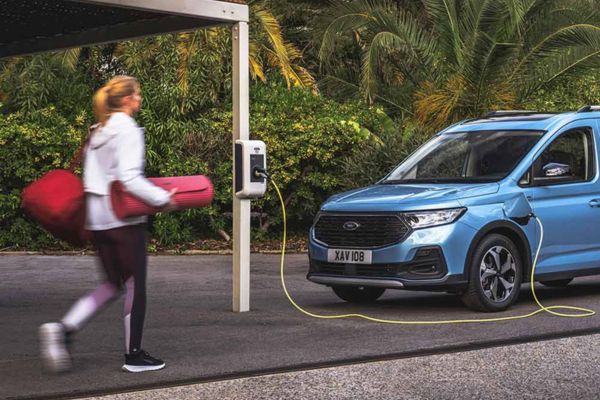 Tourneo Connect Laden Frau trägt Yogamatte zu blauem Ford-Fahrzeug