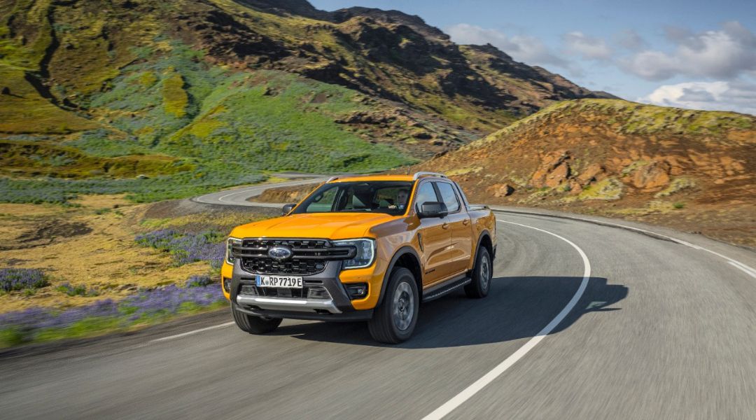 Ford Ranger Wildtrak PHEV su strada con le colline verdi