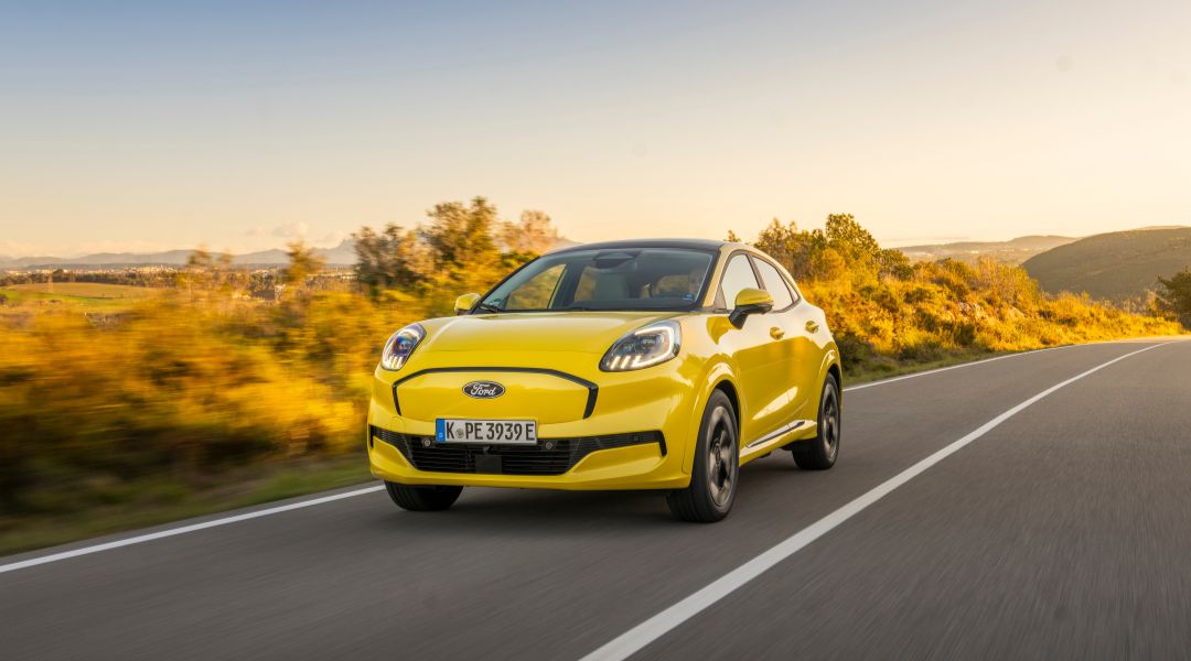 Ford Puma Gen-E gelb unterwegs auf Strasse mit bkarger Landschaft im Hintergrund