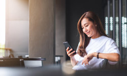 Frau sitzt auf Couch mit Smartphone