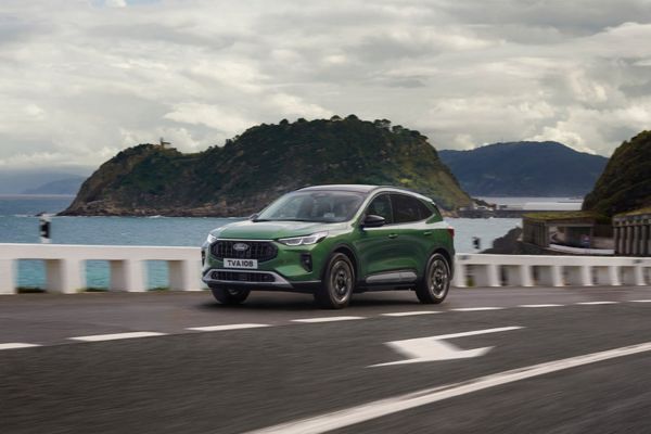 Ford Kuga verte est garée sur un parking et regarde la ville