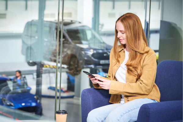 Packs protection Une femme est assise dans une salle d'attente pendant que le véhicule est réparé à l'arrière-plan
