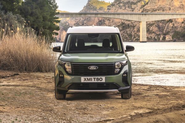 Ford Tourneo Courier sur un sol brun devant un lac sous un ciel nuageux