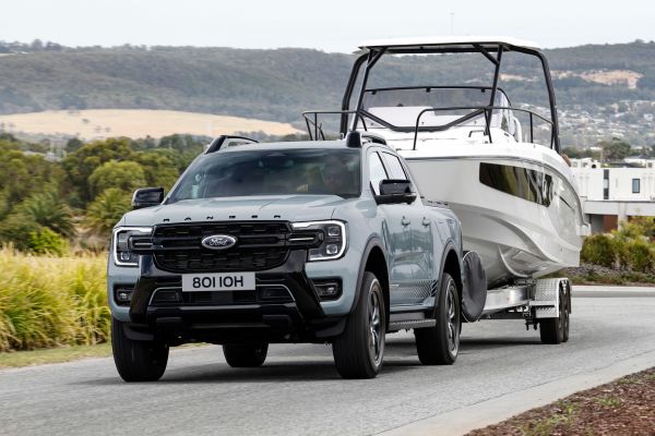 Ford Ranger PHEV Une Ford Ranger PHEV tracte un bateau le long d'une route avec la mer en arrière-plan