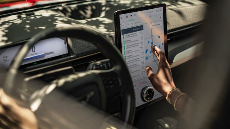 Gros plan d’une femme assise dans une Ford Mustang Mach-E, interagissant avec le grand écran tactile SYNC