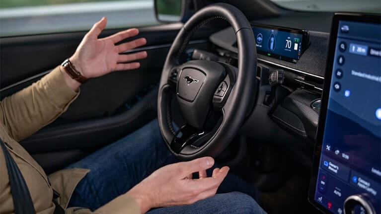 Un homme assis dans une Ford Mustang Mach-E, les mains éloignées du volant, illustrant la technologie BlueCruise