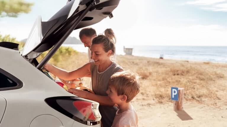 Une famille à la plage charge des affaires dans un véhicule Ford