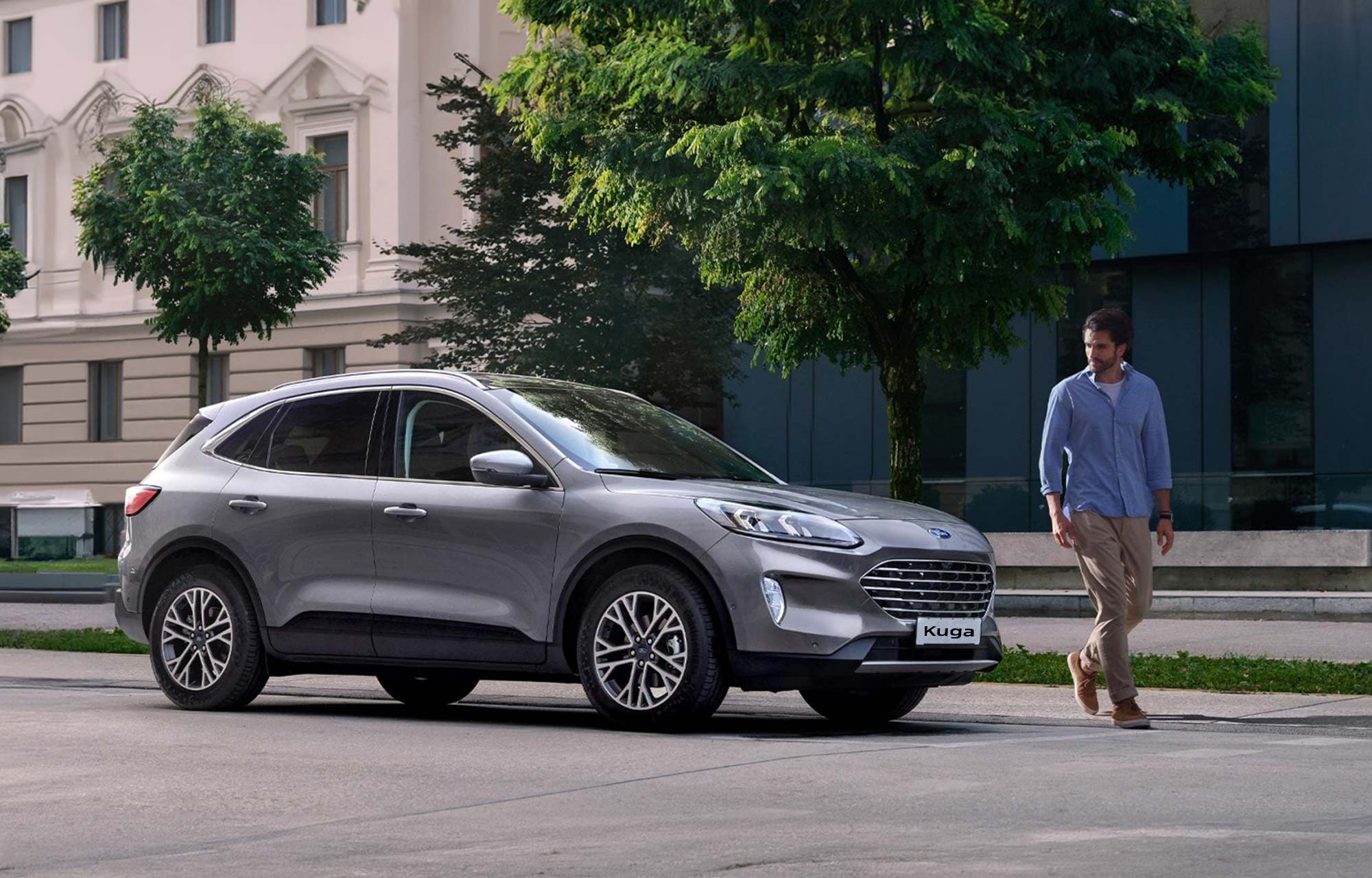 Homme marchant près d'une Ford Kuga grise
