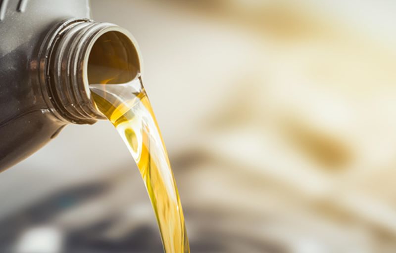 Pouring engine oil into car engine during maintenance title=