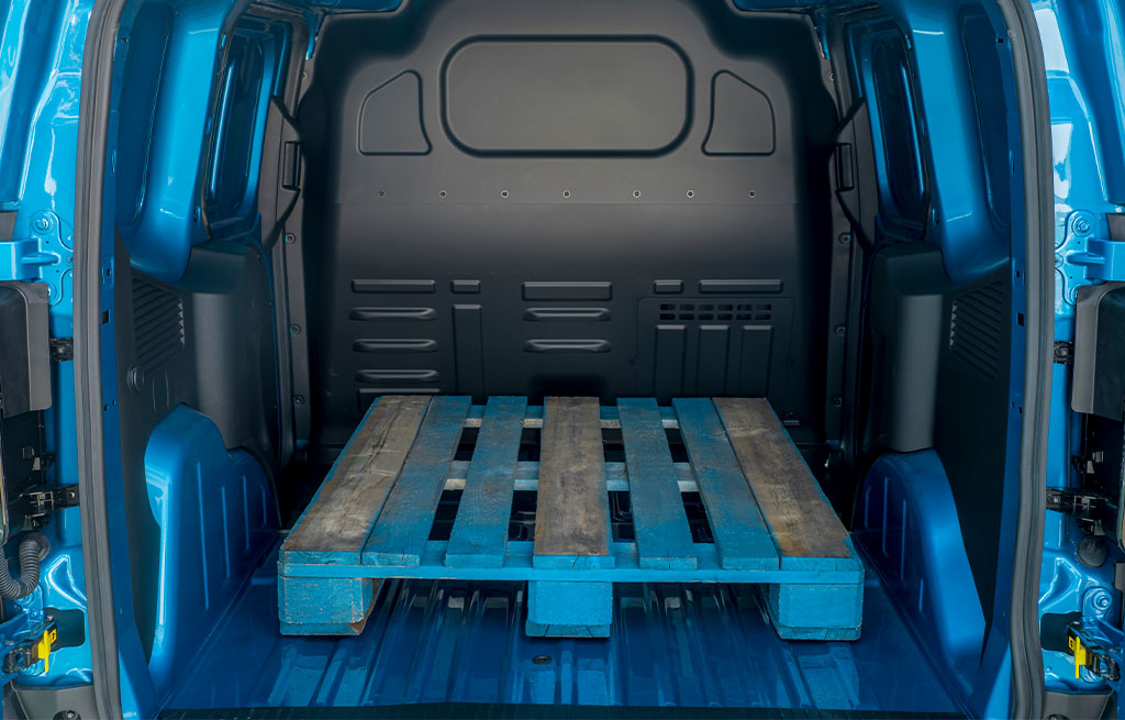 Empty blue cargo van interior with a wooden pallet in the back