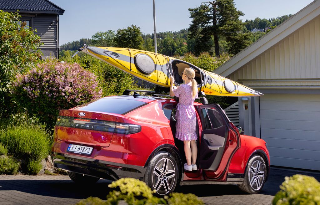 Kvinne legger kajakk på taket til Ford Capri