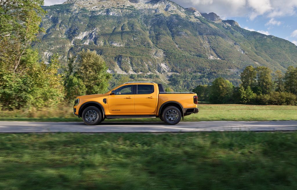 Yellow Ford Ranger driving on road with mountainous background