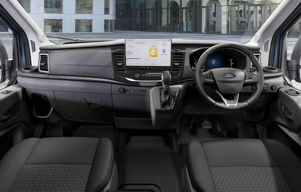 Interior cockpit of a modern Ford Transit van showing dashboard, steering wheel, touchscreen display, and front seats