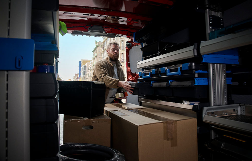 Technician organizing cargo and equipment inside a Ford Transit Custom Plug-In Hybrid van