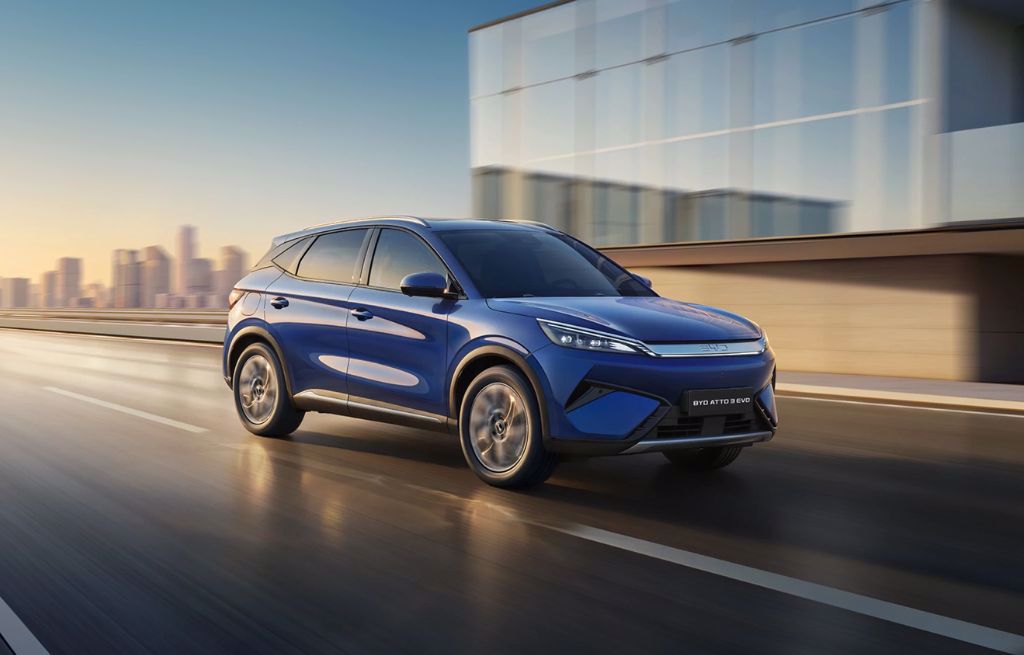 Blå BYD ATTO 3 EVO el-SUV kör på väg framför modern byggnad